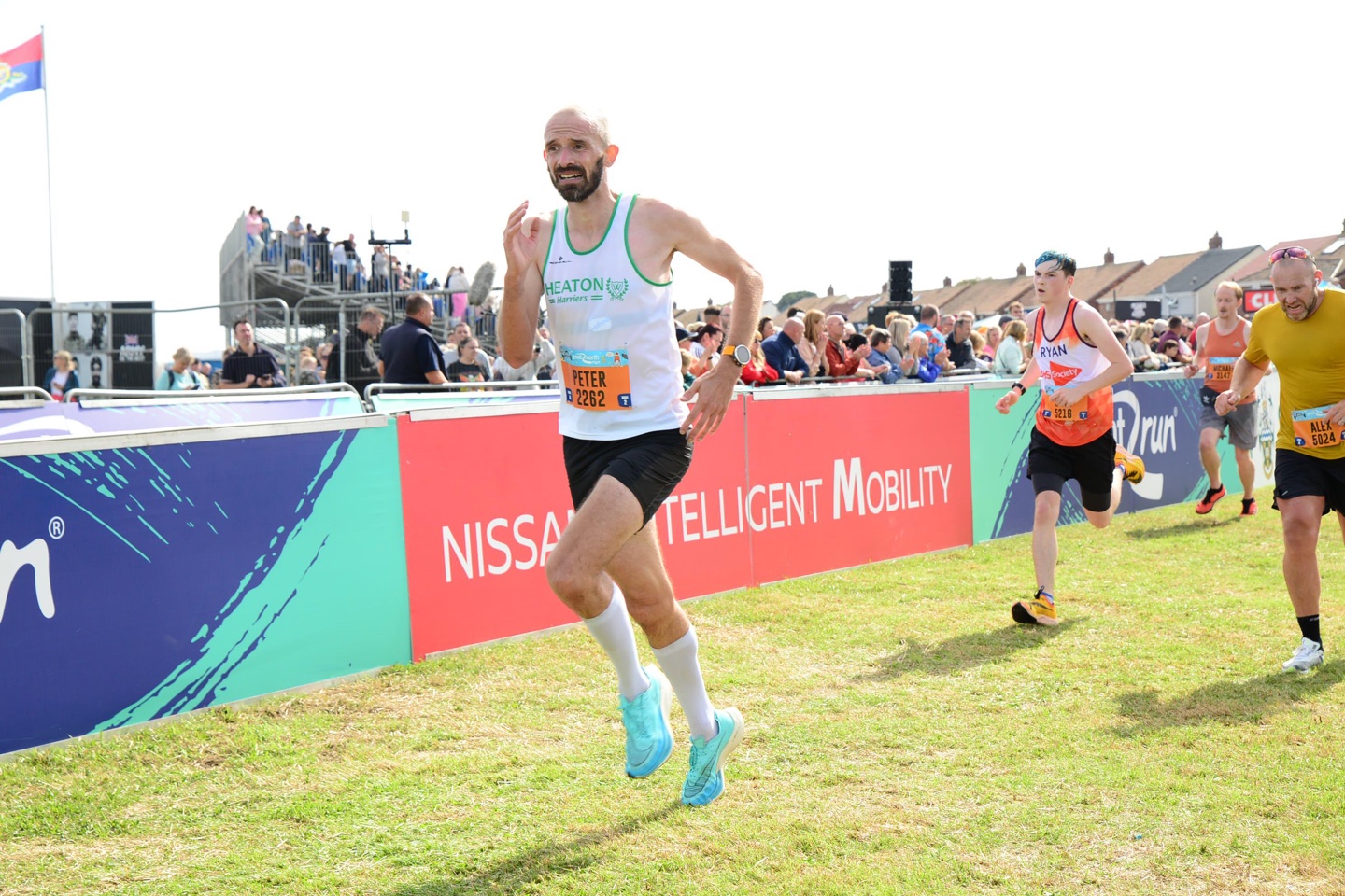 The author runs towards the finish line of the Great North Run, with a grimace on his face, wearing a white Heaton Harriers vest