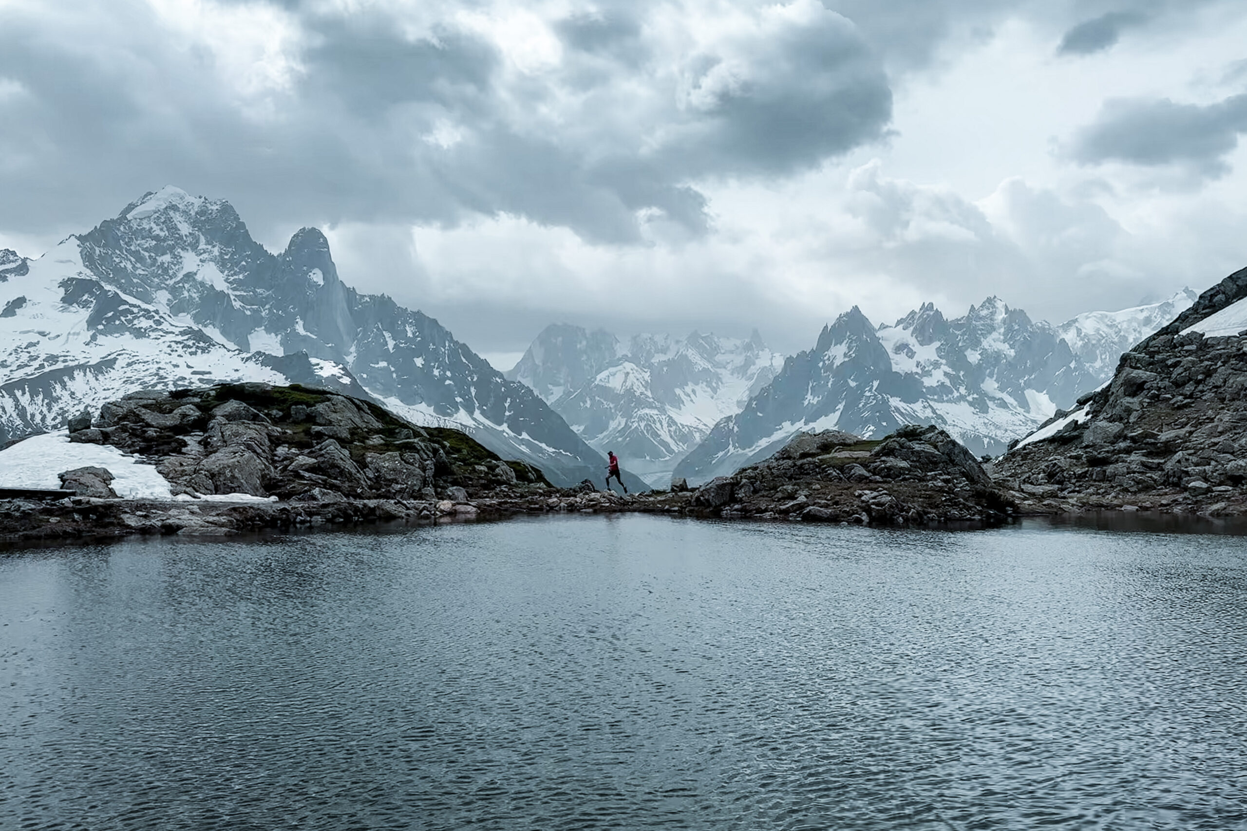 Pete running in front next to Lac Blanc, a view of Grand Jorasses behind him