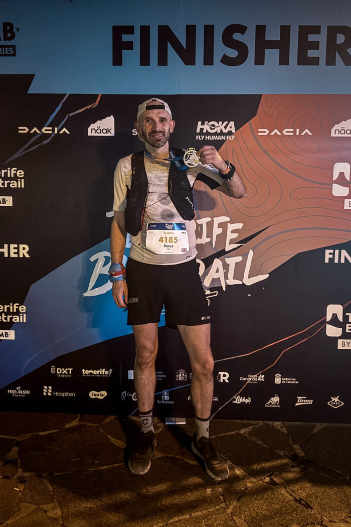 A runner stands at the finish line of Tenerife Blue Trail holding a medal