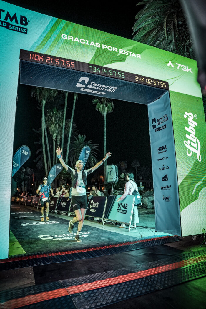 A runner runs through the finish arch of the Tenerife Blue Trail race at night