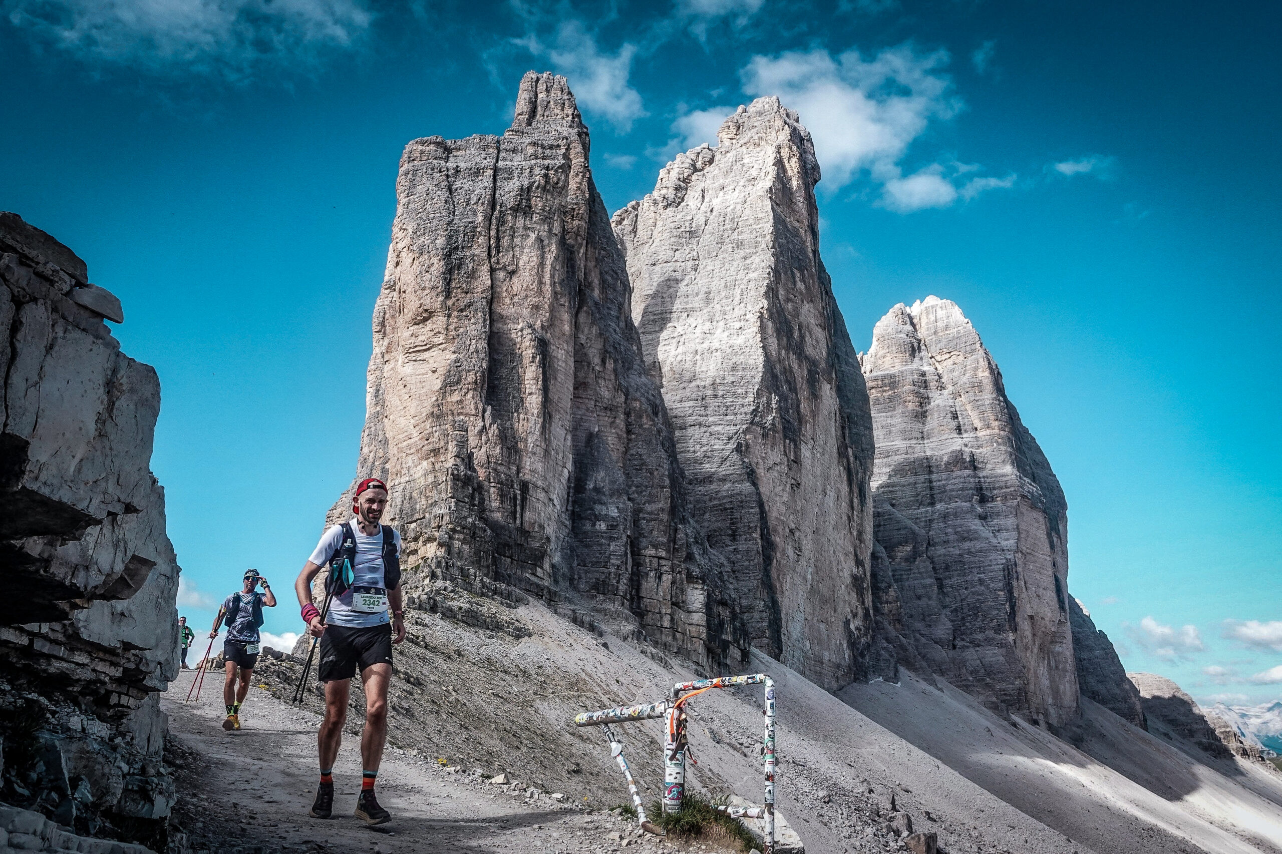 A runner runs towards the camera with a jagged mountain in the background.