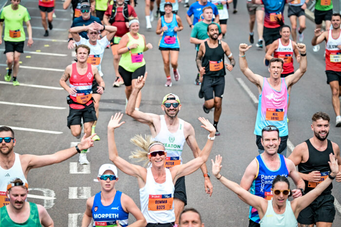 People raise their hands running towards a camera on the Great North Run