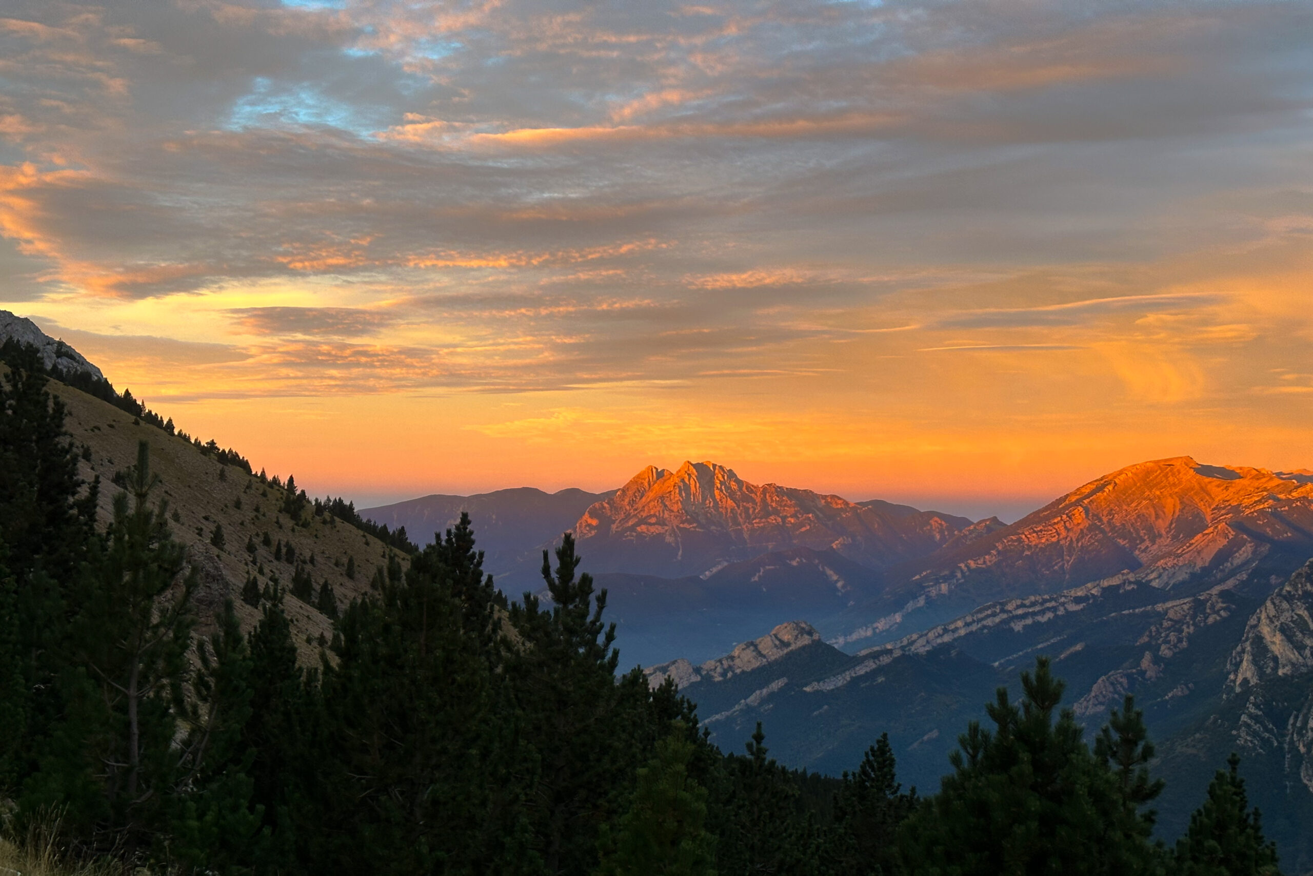Sunrise over the mountains in the pyrenees. A forest is in the foreground.
