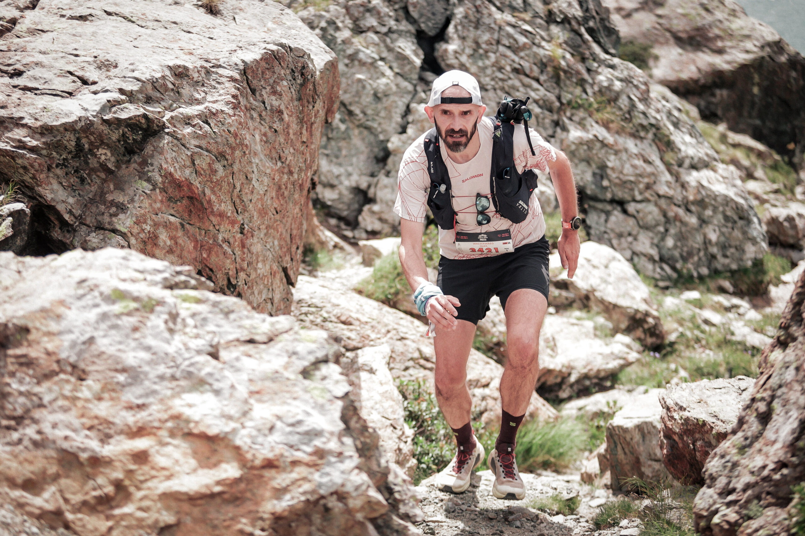 A runner runs towards the camera through a boulder filled trail