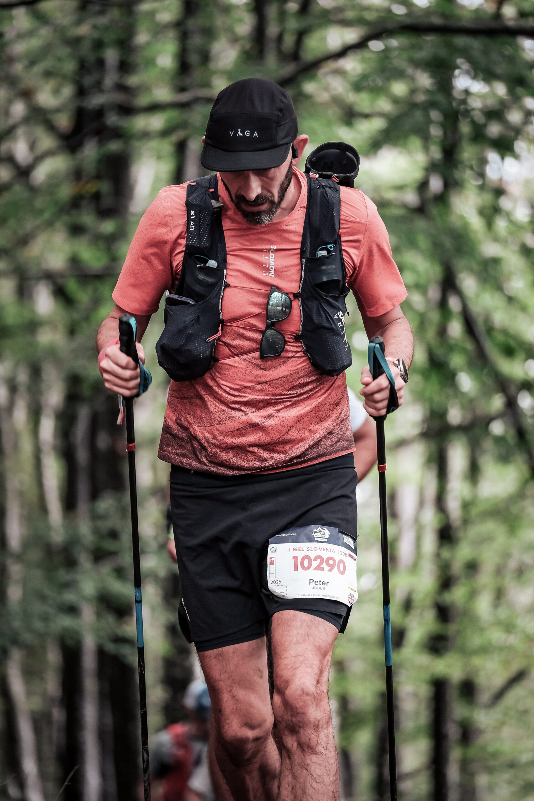 A runner moves through a forest, his head is down and he's visibly struggling.