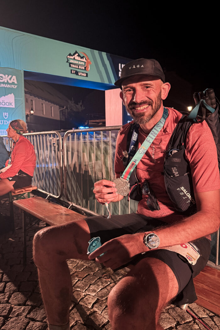 A trail runner holds his medal at the end of the Julian Alps by UTMB 120km trail race.